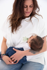 Une femme allaite son bébé et porte un hoodie en velours blanc avec une inscription brodée sur la poitrine "only love can" en vert anis. Disponible chez femininplurielles.ch