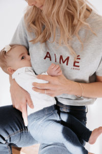 Une femme allaite son bébé. Elle porte le t-shirt gris d'allaitement Aimé Loved de la marque JALLU'S'IN